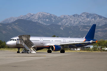 commercial aircraft at an airport, with mountainous background