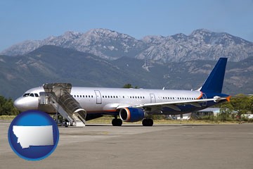 commercial aircraft at an airport, with mountainous background - with Montana icon