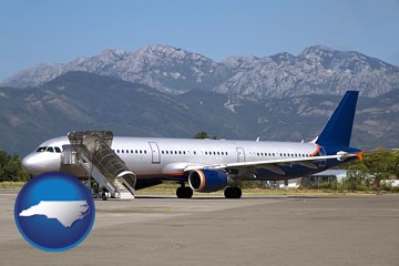 commercial aircraft at an airport, with mountainous background - with North Carolina icon