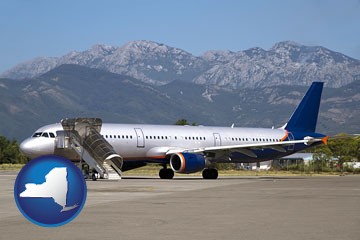 commercial aircraft at an airport, with mountainous background - with New York icon