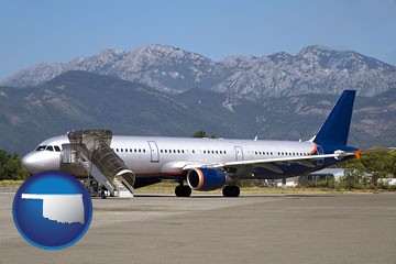 commercial aircraft at an airport, with mountainous background - with Oklahoma icon