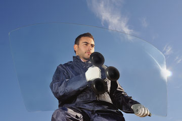 an auto glass installer holding an automobile windshield