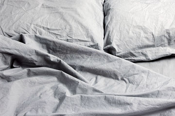 rumpled gray pillows and sheets on a bed