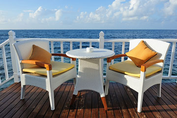 white, outdoor wicker furniture on an oceanfront deck