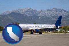 california map icon and commercial aircraft at an airport, with mountainous background