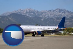 oklahoma map icon and commercial aircraft at an airport, with mountainous background