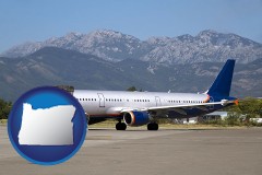 oregon map icon and commercial aircraft at an airport, with mountainous background